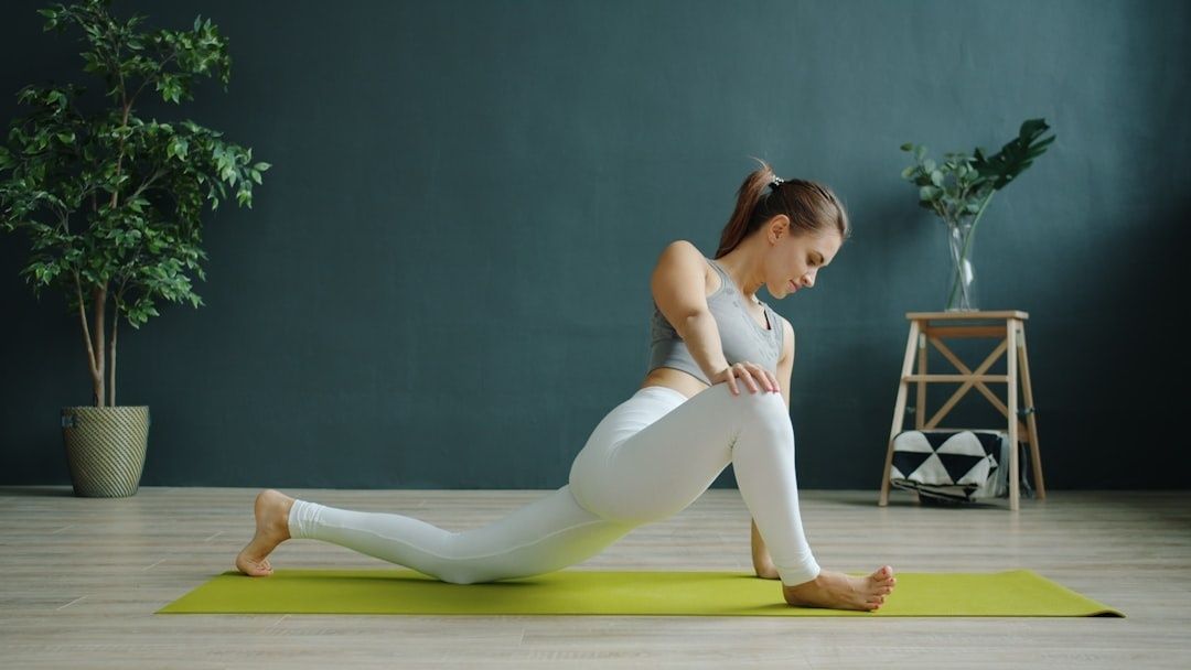 Kvinna gör en höftstretch på en yogamatta i ett vardagsrum